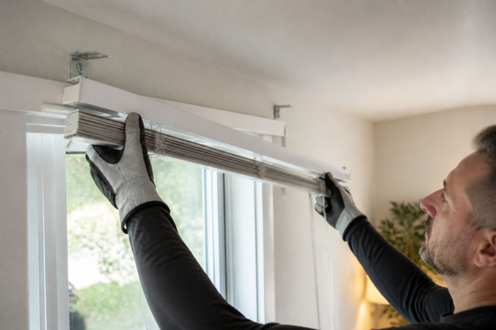Technician carefully removing blinds from window brackets